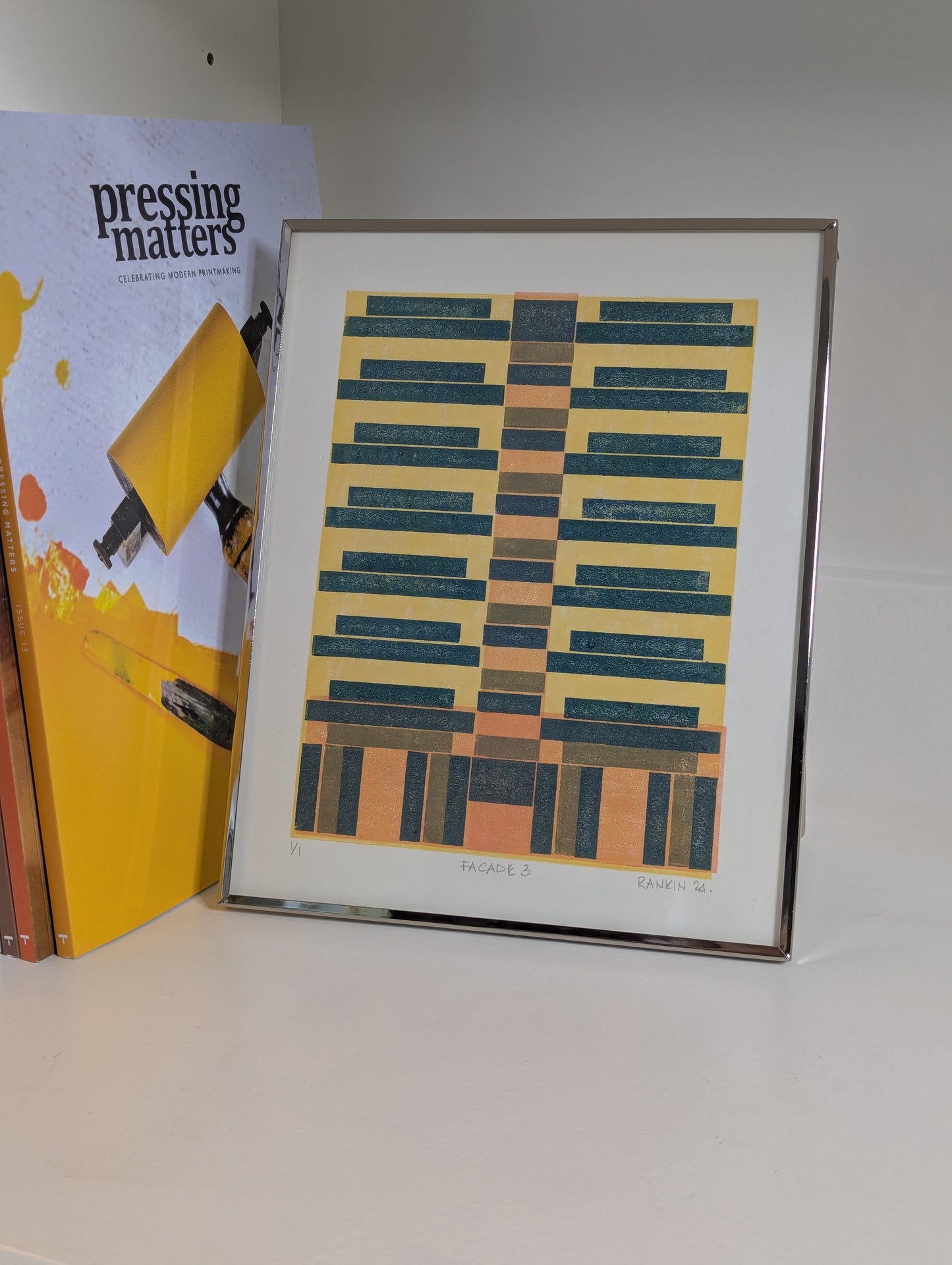 Framed geometric art print on a shelf with books